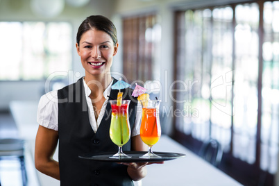 Portrait of smiling waitress serving cocktai