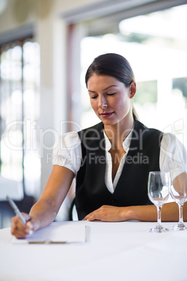 Waitress sitting at the table and making notes