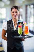 Portrait of smiling waitress serving cocktail