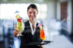 Portrait of smiling waitress serving cocktail