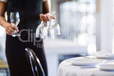 Mid section of waitress setting the table