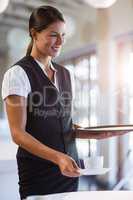Smiling waitress serving cup of coffee