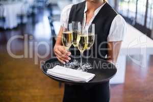 Mid section of waitress holding serving tray with champagne flutesÃ?Â 