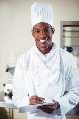Portrait of smiling chef making notes on a clipboard