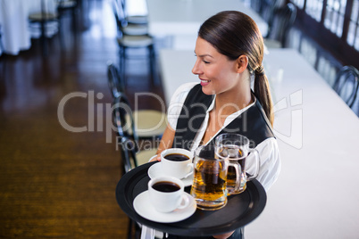 Waitress holding serving tray with coffee cup and pint of beer