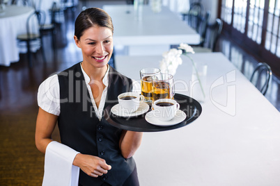 Waitress holding serving tray with coffee cup and pint of beer