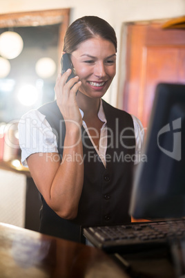 Waitress talking on a phone at counter