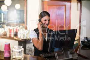 Waitress talking on a phone at counter