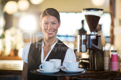 Portrait of waitress holding a tray with coffee cups