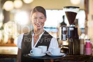 Portrait of waitress holding a tray with coffee cups