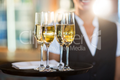 Mid section of waitress holding a serving tray with champagne flutesÃ?Â 