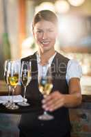 Portrait of smiling waitress offering a glass of champagne