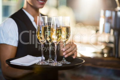 Mid section of waitress holding serving tray with champagne flutes