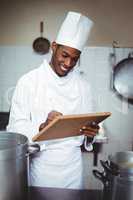 Smiling chef making notes on a clipboard