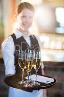 Portrait of waitress holding serving tray with champagne flutes