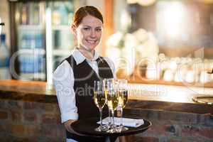 Portrait of waitress holding serving tray with champagne flutesÃ?Â 