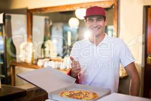 Pizza delivery man showing fresh pizza and thumbs up