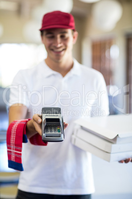 Happy pizza delivery man showing credit card machine