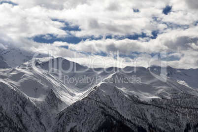View on snowy mountains and sunlight cloudy sky in evening