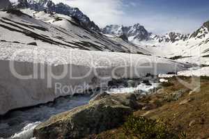 River with snow bridges in spring mountains at sun day