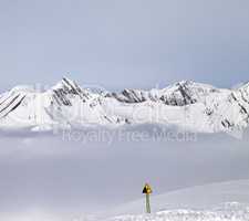 Mountains in mist and warning sing on ski slope