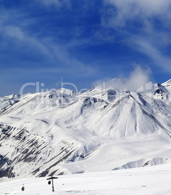 Winter snowy mountains and ski slope at sun day