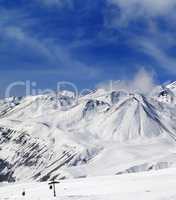 Winter snowy mountains and ski slope at sun day