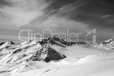 Black and white view on off-piste slope at sun evening