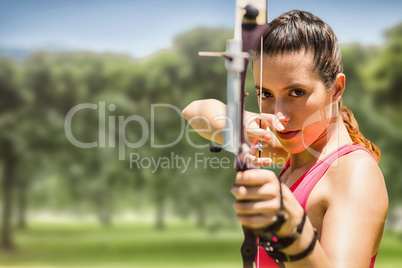 Composite image of portrait of sportswoman practising archery