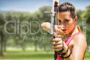 Composite image of portrait of sportswoman practising archery