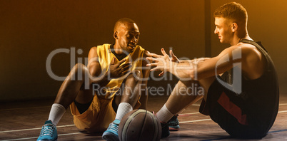 Basketball players sitting on floor talking together