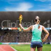 Composite image of rear view of sporty woman holding olympic tor
