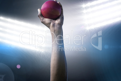 Composite image of hand holding a red ball