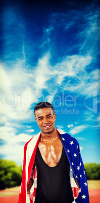 Athlete with american flag wrapped around his body against athle