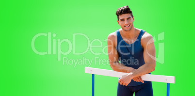 Portrait of sportsman is smiling and posing on a hurdle