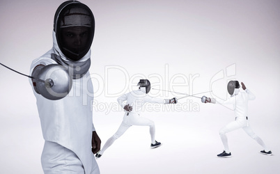 Composite image of man wearing fencing suit practicing with swor