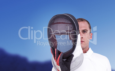 Composite image of swordsman holding fencing mask