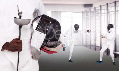 Composite image of mid-section of man standing with fencing mask