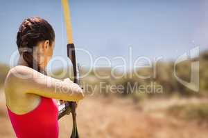 Composite image of rear view of sportswoman doing archery on a w