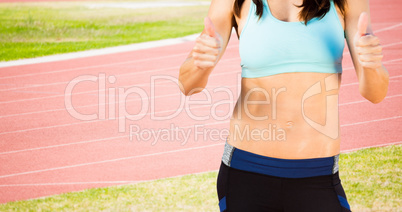 Composite image of portrait of sporty woman smiling with thumbs