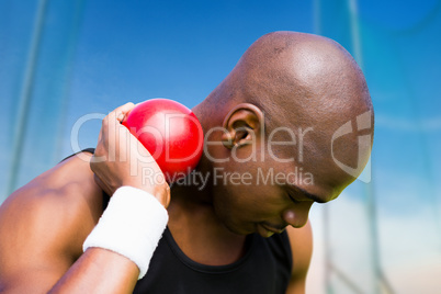 Composite image of portrait of sportsman practising shot put