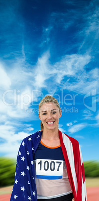 Athlete with american flag wrapped around his body against athle