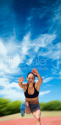 Sportswoman jumping against athletics field
