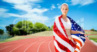 Portrait of sporty woman holding American flag against athletics