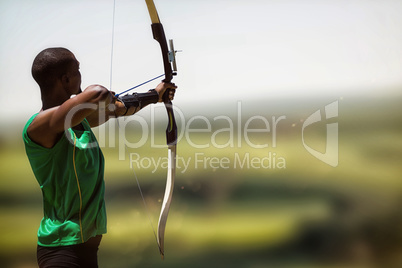 Composite image of rear view of sportsman doing archery on a whi