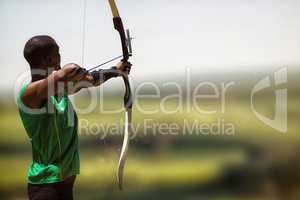 Composite image of rear view of sportsman doing archery on a whi