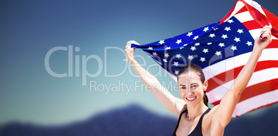 Portrait of happy sportswoman raising an american flag
