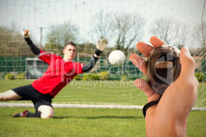 Composite image of coach is holding a stopwatch against goalkeep