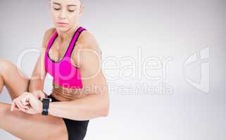 Composite image of female athlete sitting and using her smart wa
