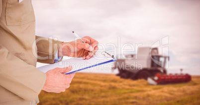 Composite image of delivery man writing on clipboard